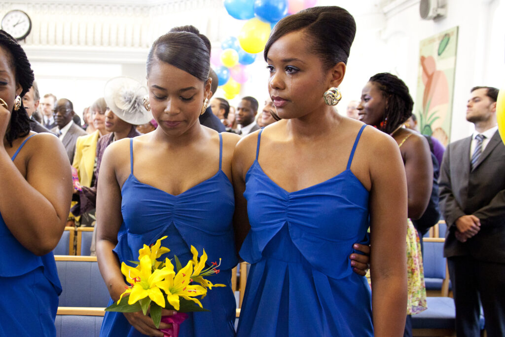 Colour photograph of bridesmaids dressed in blue crying as vows are said