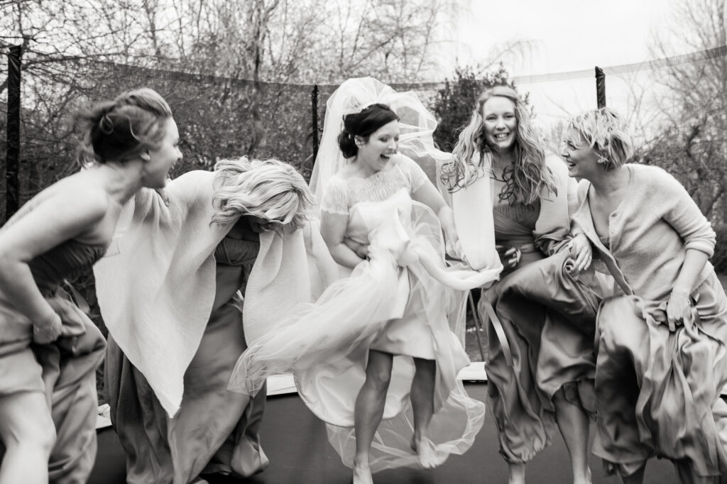 Bride and bridesmaids jumping on a trampoline at the wedding reception by documentary ottawa wedding photographer sara